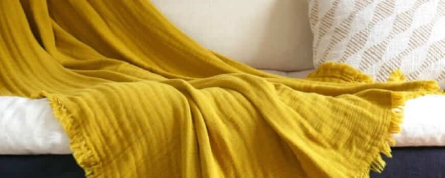 Plaid jaune moutarde en gaze de coton à franges sur un canapé – Plaid Addict