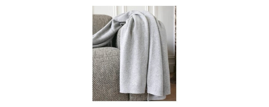Plaid gris clair en maille douce drapé sur un canapé chiné – Plaid Addict