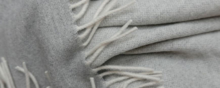 Détail d'un plaid en laine gris perle à franges, matière douce – Plaid Addict