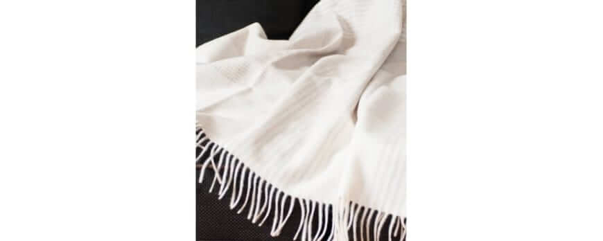 Plaid en cachemire blanc cassé à franges sur fond sombre – Plaid Addict
