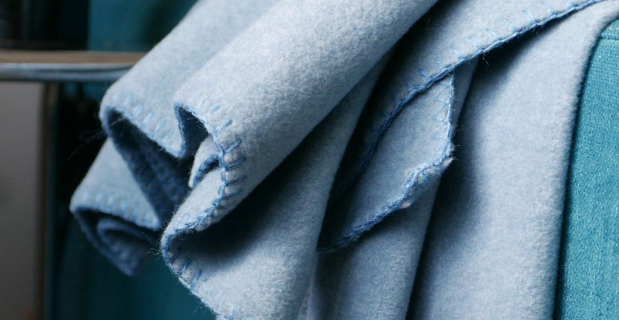 Plaid bleu ciel en laine feutrée au bord surfilé, plié en drapé – Plaid Addict