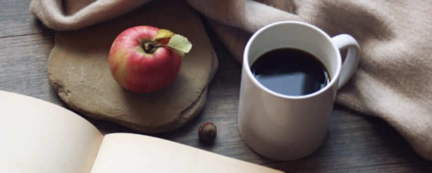 Tasse de café, livre ouvert et plaid beige, ambiance cosy pour l'hiver