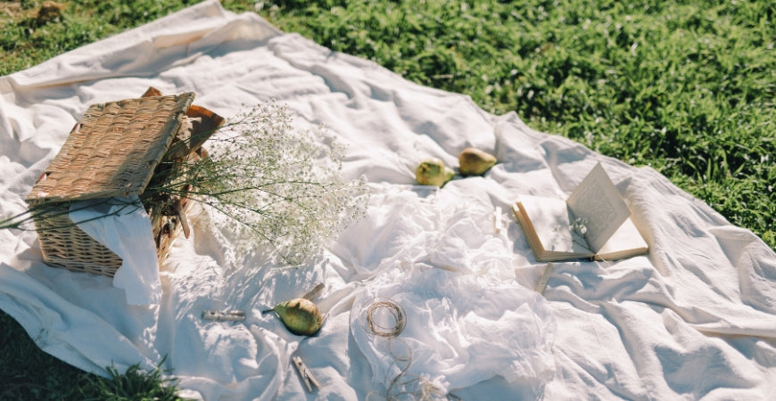 Plaid blanc léger étendu dans l'herbe pour un pique-nique champêtre