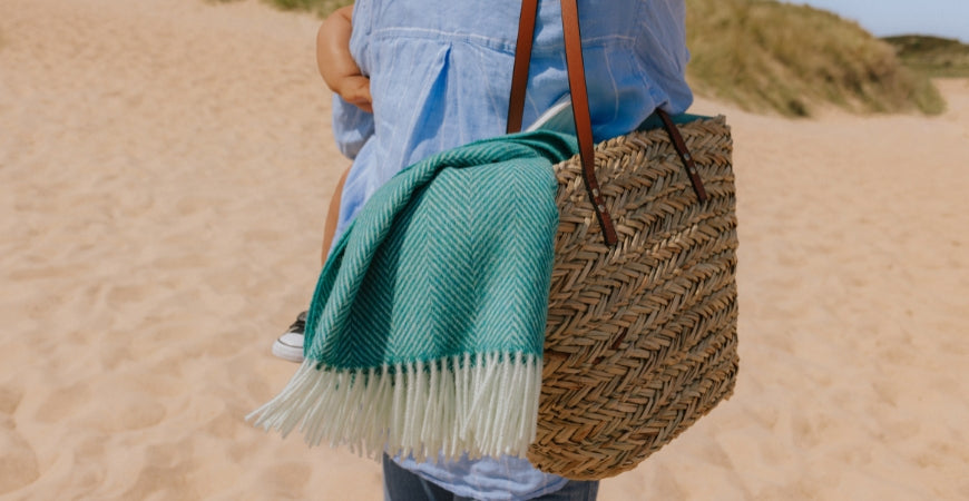 Plaid émeraude à chevrons dépassant d'un panier en osier à la plage – Plaid Addict