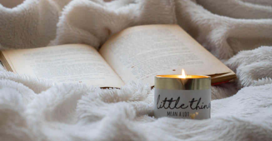 Livre ouvert et bougie sur un plaid blanc moelleux, ambiance cocooning – Plaid Addict