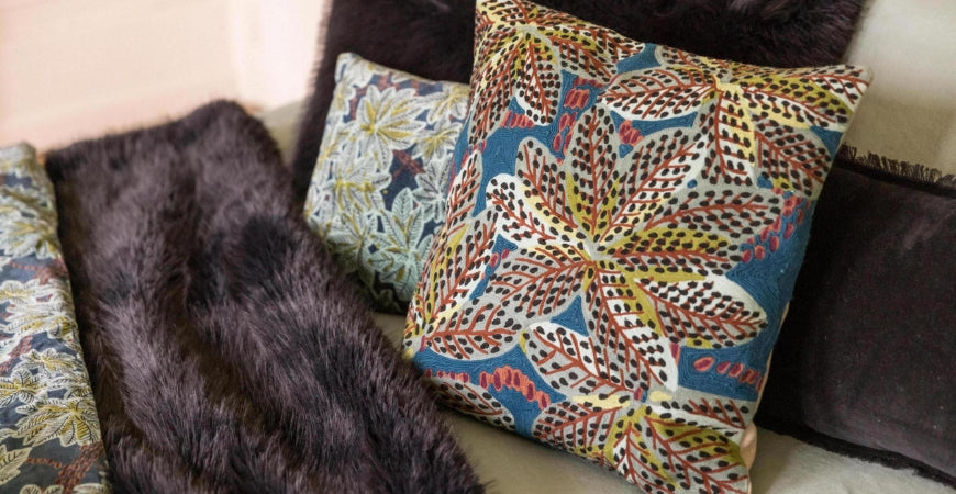 Plaid en fausse fourrure chocolat et coussins imprimés sur un canapé – Plaid Addict