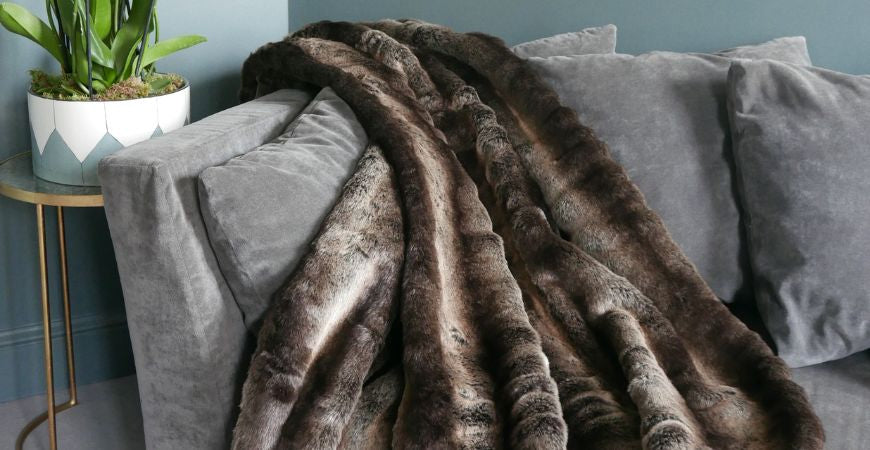 Grand plaid en fausse fourrure taupe chiné drapé sur un canapé gris – Plaid Addict