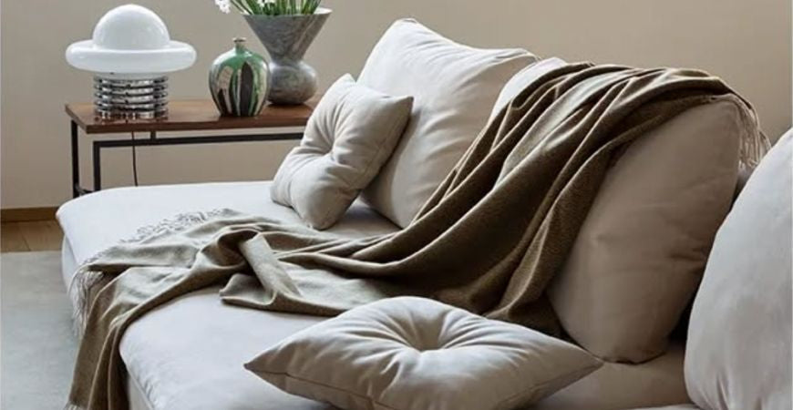 Plaid taupe drapé avec coussins assortis sur un canapé beige élégant – Plaid Addict
