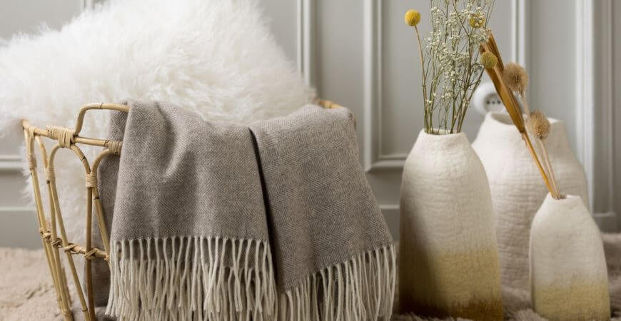 Plaid taupe à franges sur un fauteuil en rotin avec vases artisanaux – Plaid Addict