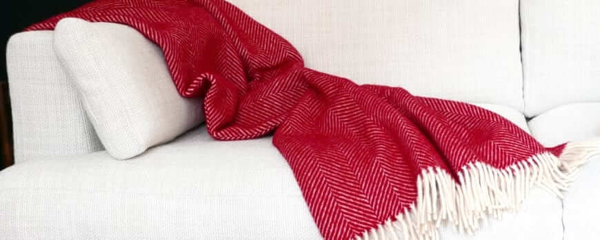 Plaid rouge à chevrons en laine avec franges jeté sur un canapé blanc – Plaid Addict