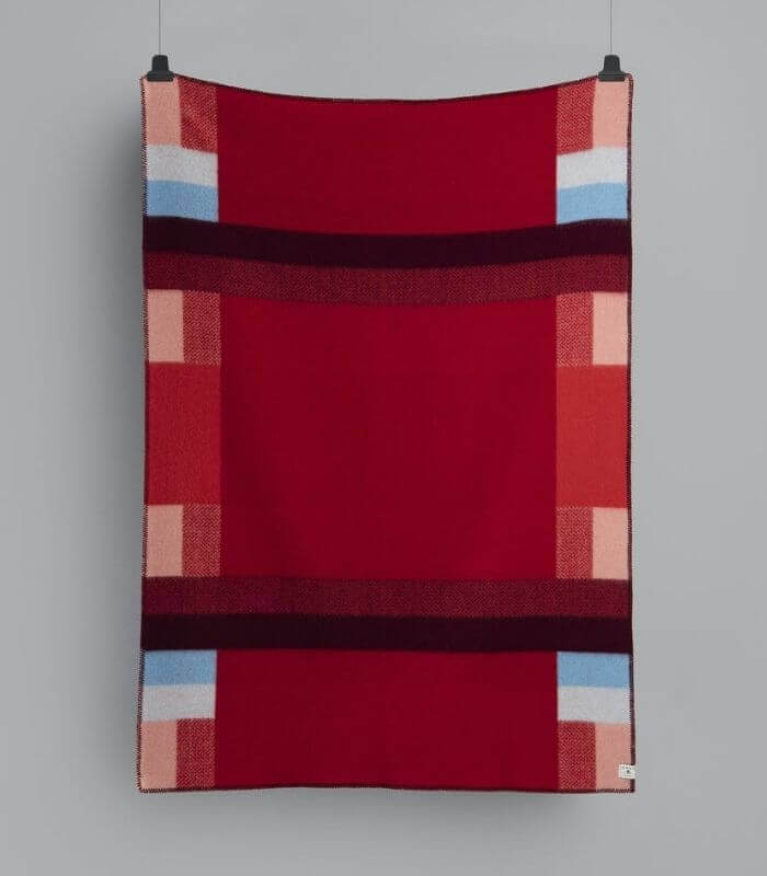 Plaid Pure Laine Mikkel Rouge 135 x 200 cm, Roros Tweed, drapé sur un canapé