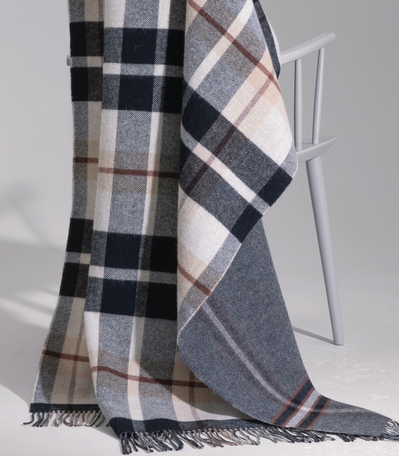 Plaid Laine Écossais Réversible Luxe Noir et Beige 140 x 190 cm, Johnstons of Elgin, drapé sur un canapé