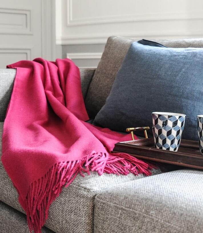 Plaid Laine Alpaga Luxe Framboise 130 x 180cm, Casa Paola, drapé sur un canapé