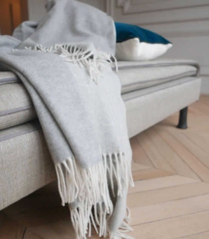 Plaid Cachemire Reversible Gris et Ecru - Collection VENICE 140 x 210 cm, Plaid Addict, drapé sur un canapé