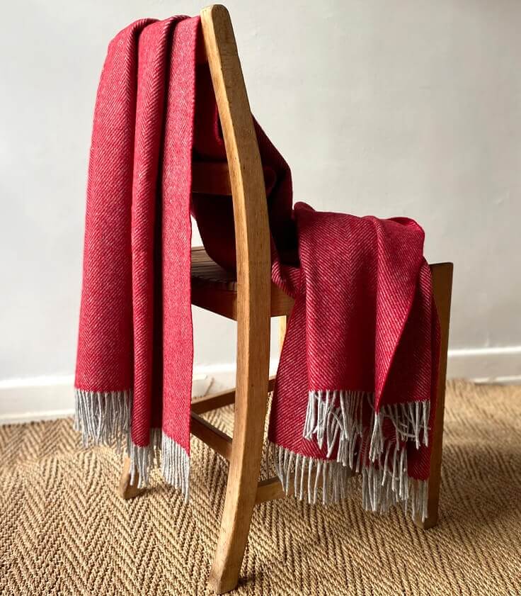 Plaid Laine Mérinos Chevrons Rouge, Plaid Addict, drapé sur un canapé
