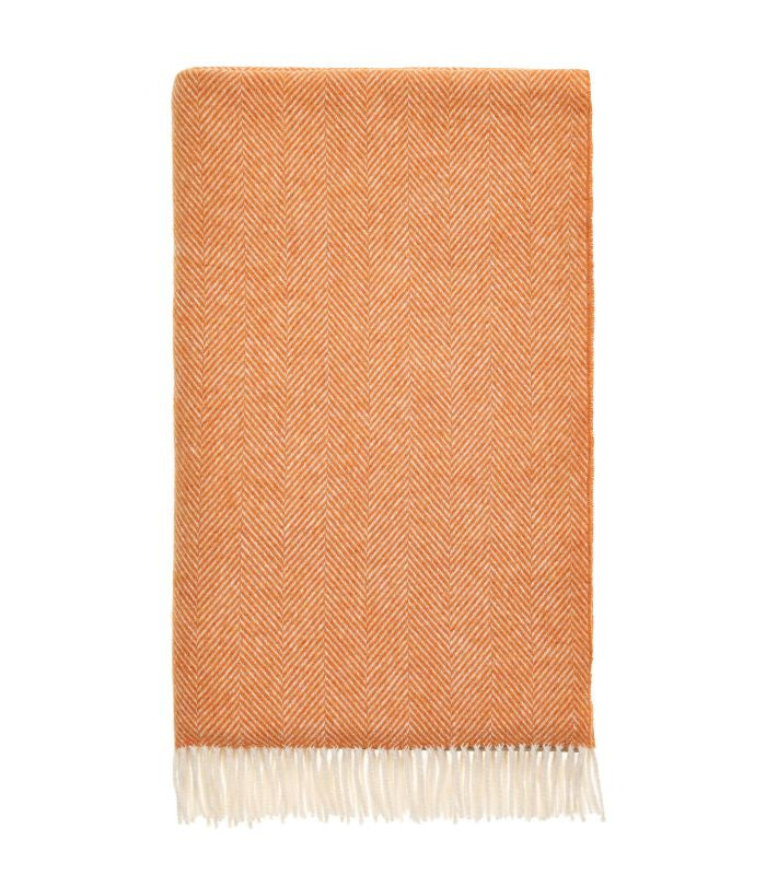 Plaid Laine Mérinos Chevrons Orange, B at Home, drapé sur un canapé