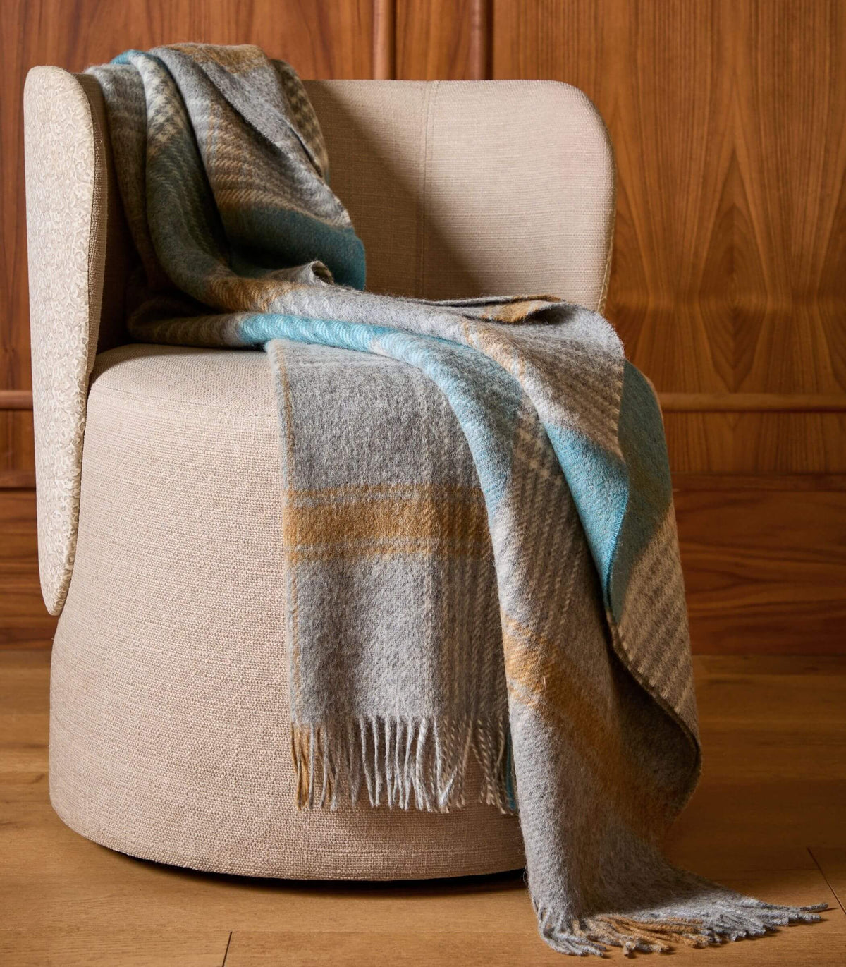 Plaid en laine à carreaux écossais gris et bleu drapé sur un fauteuil