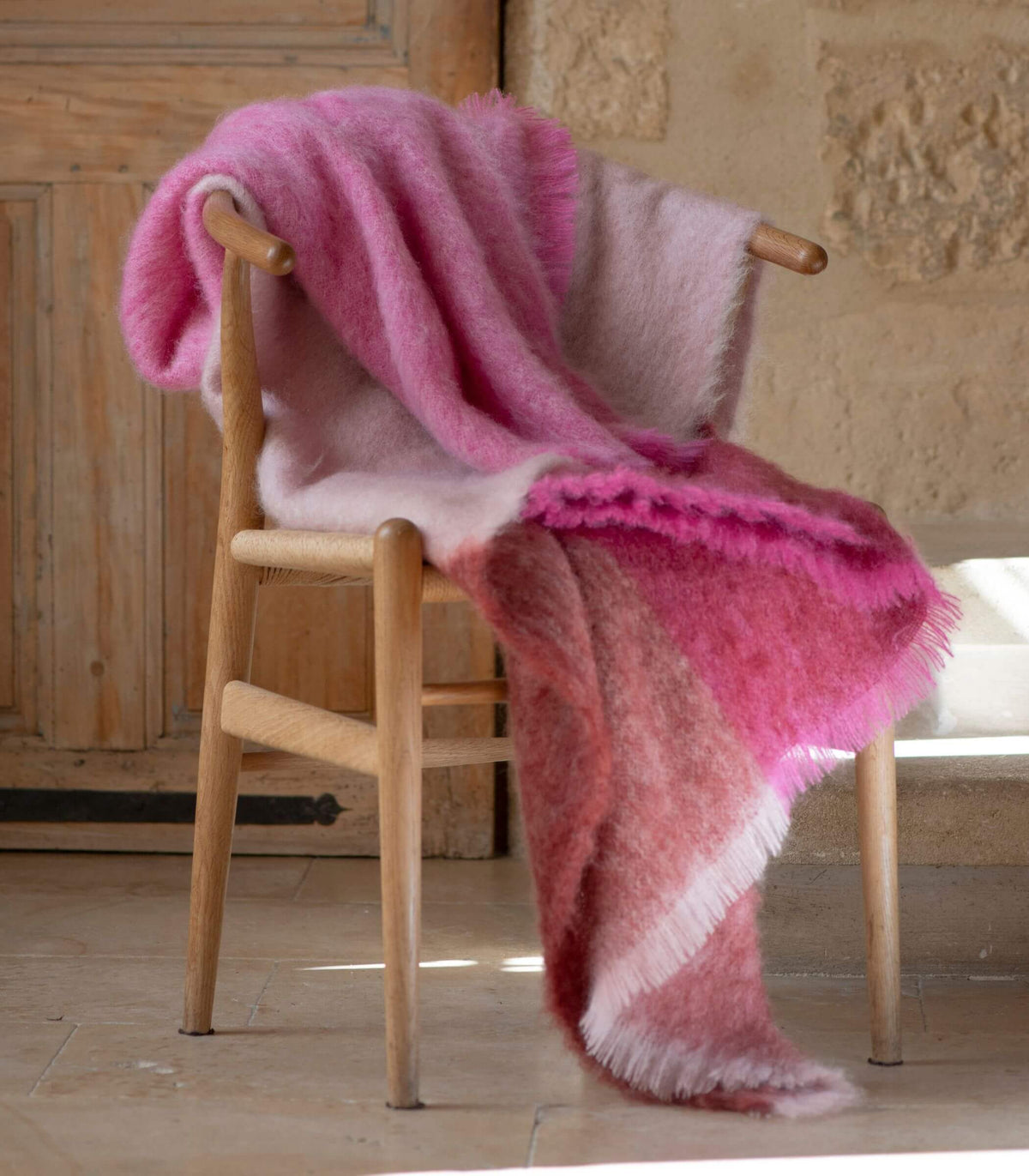 Plaid mohair rose à grands carreaux posé sur un fauteuil en bois